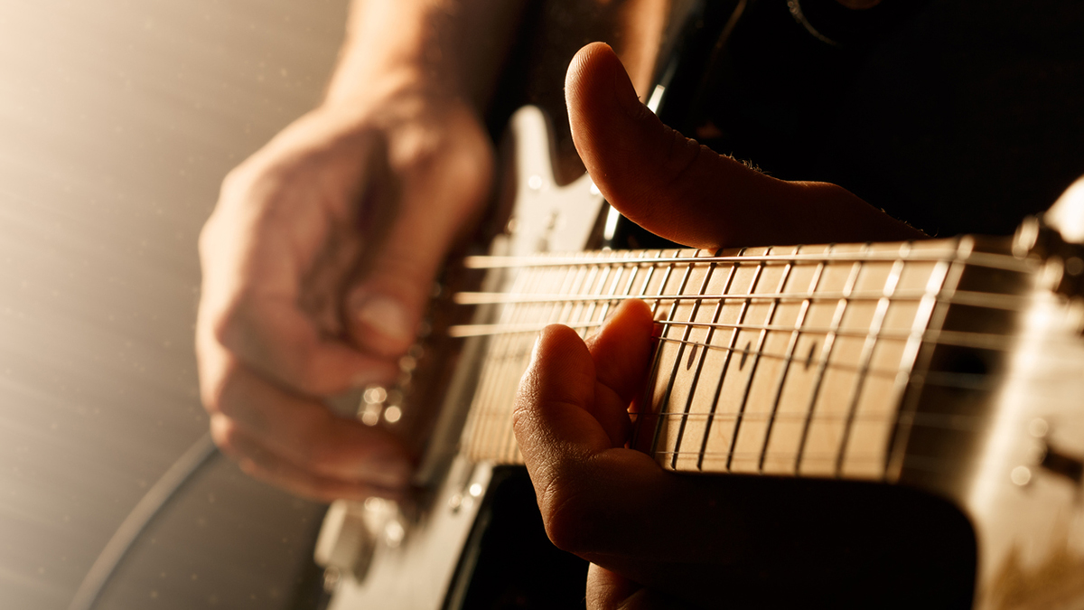 A close up of hands playing a guitar